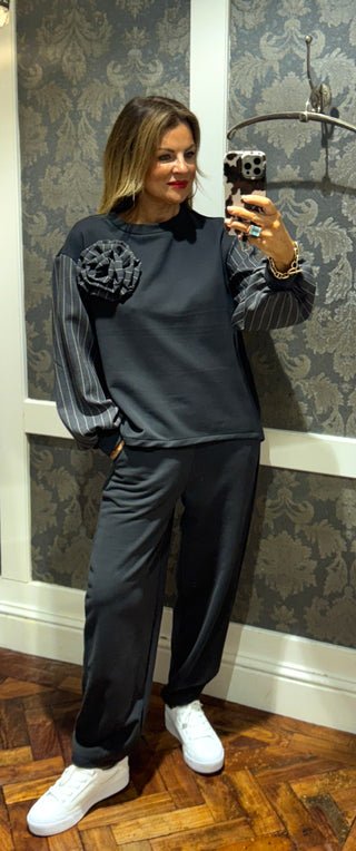 Combining comfy and chic, this two-piece features a sleek straight-leg fit with stylish pinstripe detailing on the sleeves, pockets, and a statement pinstripe rose. Combining sporty comfort with tailored elegance, it’s the perfect blend of casual and sophisticated.