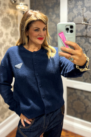 Elevate your wardrobe with the Parada Navy Knit, featuring a refined button-up front adorned with Prada-inspired embellishments. Its deep navy tone and elegant details offer a timeless, sophisticated look perfect for both professional settings and polished casual wear. Crafted to combine style and subtle luxury, this knit promises lasting appeal and versatility.