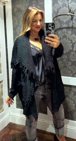 Blend of style and comfort with this knitted black poncho. Featuring a chunky knit texture and a chic fold-over collar, it offers cozy warmth while making a bold fashion statement. Elevate your wardrobe instantly with this versatile piece that effortlessly transforms any outfit into a sophisticated look.