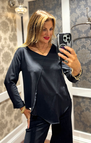 This black long sleeve top features stylish 3/4 length cuffed sleeves for a polished touch. The asymmetrical neckline and hem create a modern silhouette, while the stitch detail across the front adds unique character. Perfect for those who appreciate subtle, distinctive design that sets you apart effortlessly.