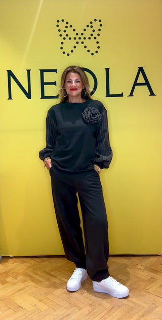 Combining comfy and chic, this two-piece features a sleek straight-leg fit with stylish pinstripe detailing on the sleeves, pockets, and a statement pinstripe rose. Combining sporty comfort with tailored elegance, it’s the perfect blend of casual and sophisticated.