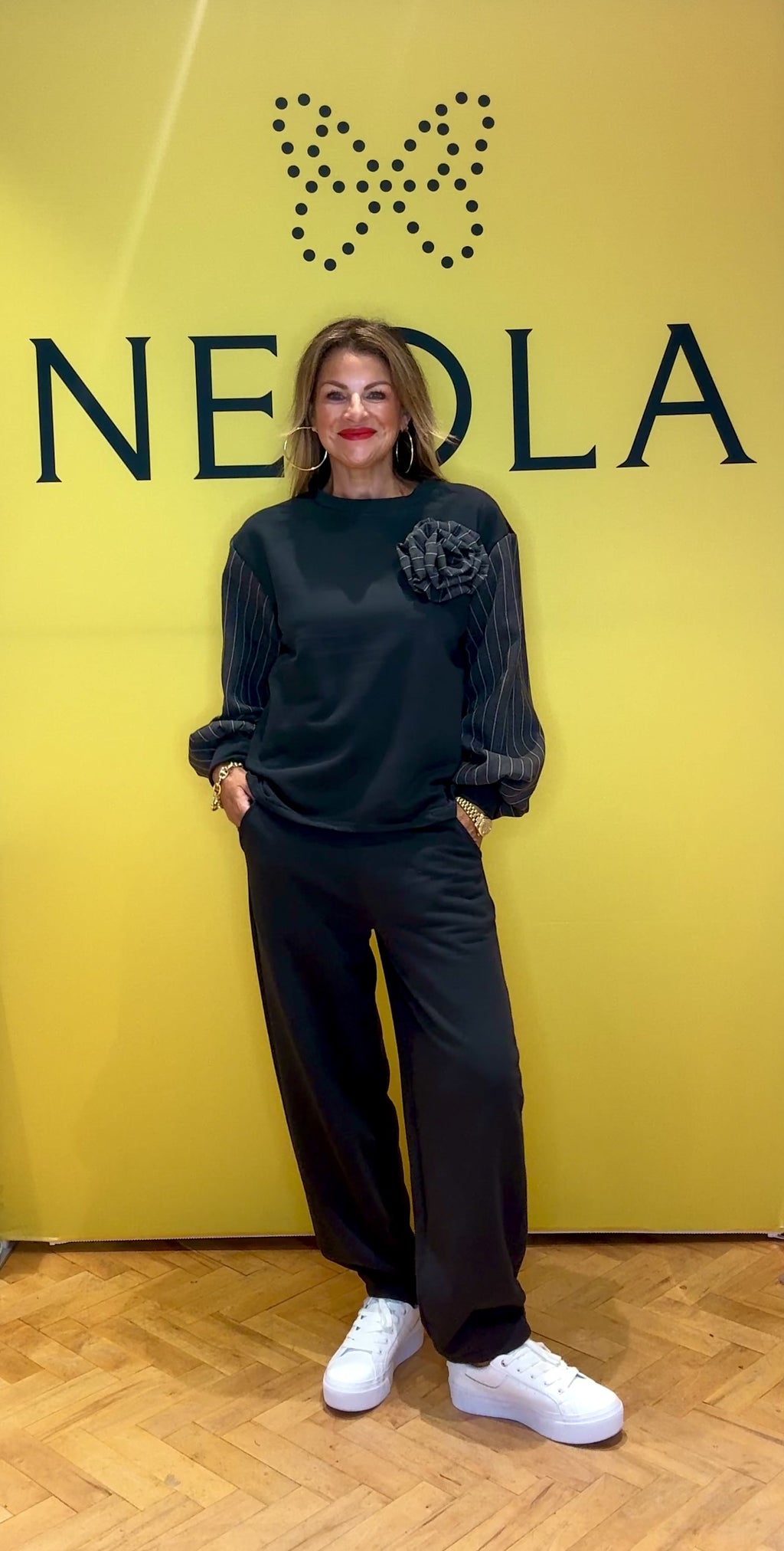 Combining comfy and chic, this two-piece features a sleek straight-leg fit with stylish pinstripe detailing on the sleeves, pockets, and a statement pinstripe rose. Combining sporty comfort with tailored elegance, it’s the perfect blend of casual and sophisticated.