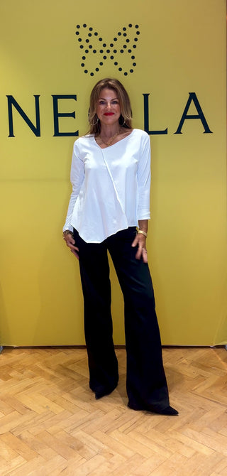 This white long sleeve top features stylish 3/4 length cuffed sleeves for a polished touch. The asymmetrical neckline and hem create a modern silhouette, while the stitch detail across the front adds unique character. Perfect for those who appreciate subtle, distinctive design that sets you apart effortlessly.